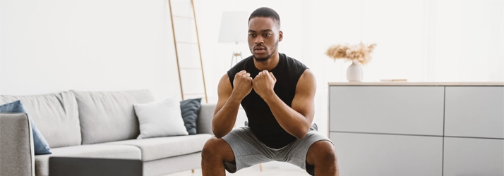 Chiropractic Allen TX Man Balancing A man squatting in a living room.
